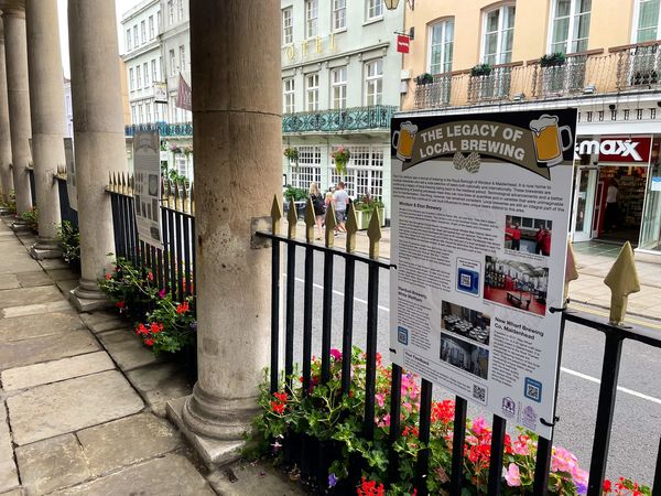 Exterior view of historic Corn Exchange showcasing an exhibition titled 'The Legacy of Local Brewing' with informative panels and flowers in the foreground.