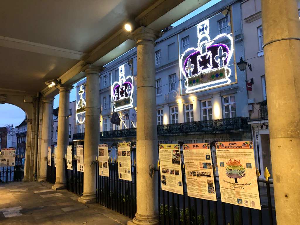 Exterior view of the historic Corn Exchange showcasing illuminated crown decorations and exhibition panels highlighting the Museum's history.