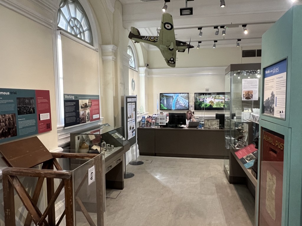 Interior view of the Windsor Museum featuring displays, information boards, and a staff member at the reception desk.