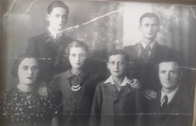 Black and white photograph of the Kestenberg family, consisting of three boys, two girls, and two adults, posing together indoors.