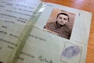 Historical identification document of a Holocaust survivor, featuring a black and white photograph of a young boy in a concentration camp uniform.