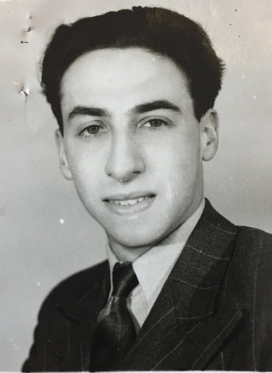Black and white portrait of a young man (Manny Silver) with dark hair, wearing a suit and tie, smiling at the camera.