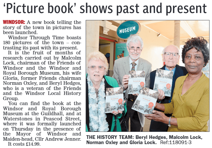 Members holding copies of the book 'Windsor Through Time' at the Windsor and Royal Borough Museum, with a sign indicating 'MUSEUM' in the background.