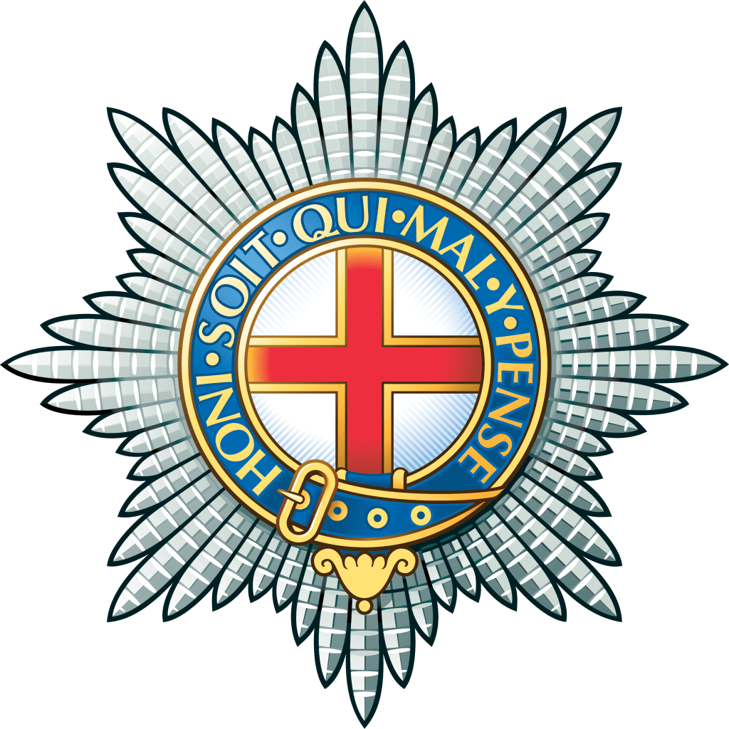 Emblem of the Coldstream Guards featuring a red cross and a golden belt buckle, surrounded by a circular blue band with the motto 'Honi Soit Qui Mal Y Pense' on a silver background.