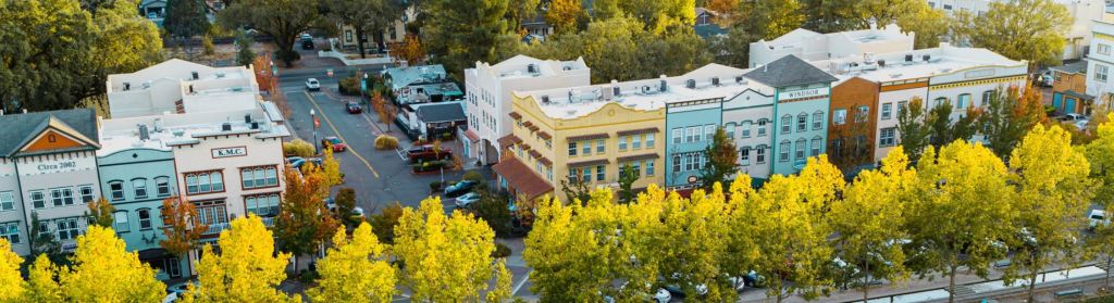 Aerial view of the charming town with colorful buildings and tree-lined streets, showcasing the vibrant community atmosphere of Windsor, California.