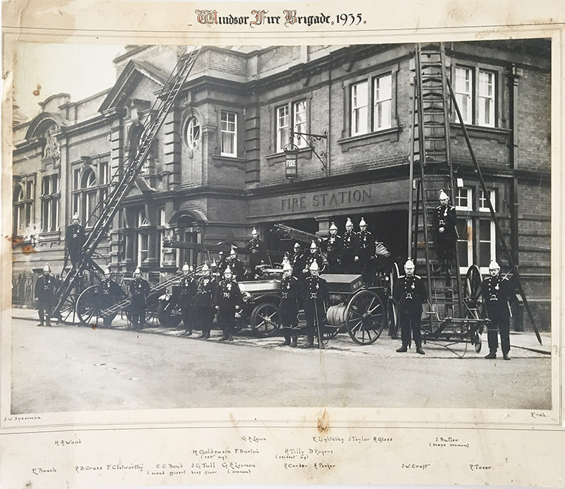 Historical photograph of the Windsor Fire Brigade in 1935, featuring firemen in uniforms, a fire engine, and a fire station with ladders and equipment.