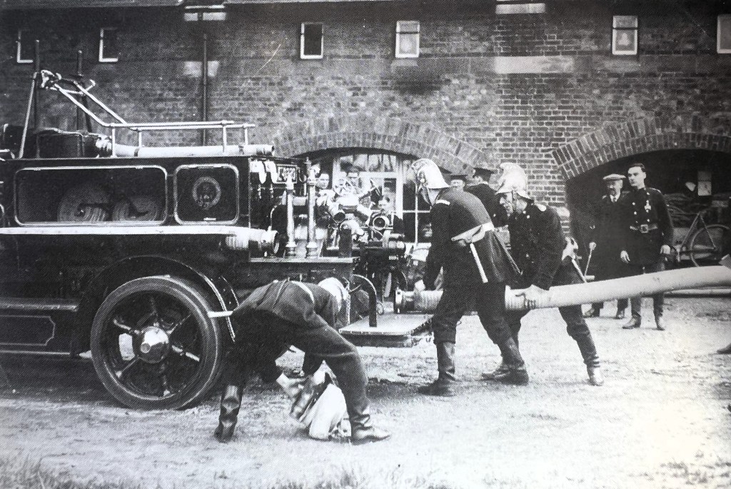 Historical photograph of Windsor's firefighters actively managing a fire engine, demonstrating teamwork and dedication in emergency response.